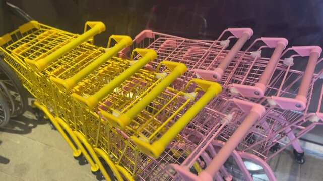 Small yellow and pink shopping carts in close-up with vibrant color contrast
