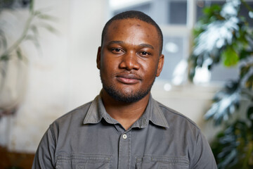 Fototapeta premium Portrait of a Confident Man Smiling in a Bright Indoor Setting With a Natural Background