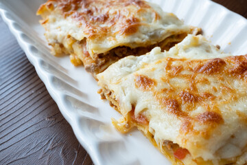 Close-up of homemade Italian lasagna on a square white plate	