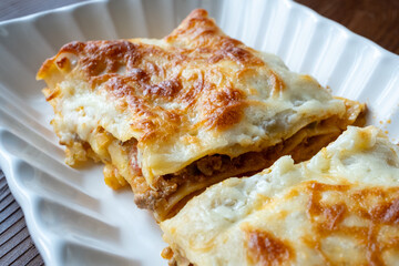 Close-up of homemade Italian lasagna on a square white plate	
