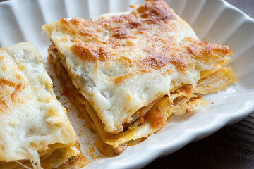 Close-up of homemade Italian lasagna on a square white plate	
