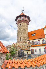 Obraz premium Hnevin Castle stands prominently in Most, Czechia, featuring a mix of stone and modern elements. The orange roofs complement the castle's historic grandeur under a cloudy sky.