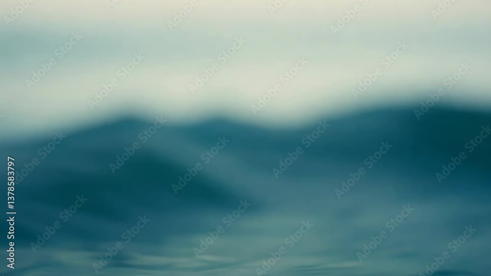 Poster a blurry image of the ocean with a wave. the water is blue and the sky is cloudy