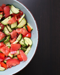 Fresh vegetable salad made of sliced tomatoes, cucumbers, and bell peppers in a deep bowl, sprinkled with ground black pepper. A healthy and colorful dish, perfect for a balanced diet, vegetarian meal