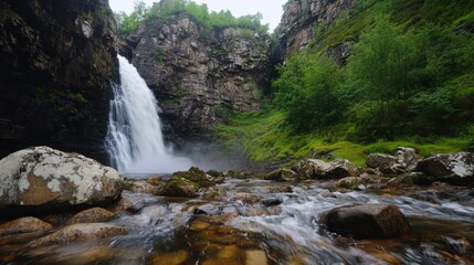 Fototapeta premium Majestic waterfall cascading in lush green forested canyon landscape