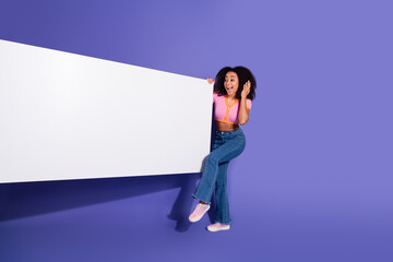 Joyful young woman posing with a blank white banner, gesturing enthusiastically against a vibrant...