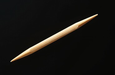 Single toothpick on black background. Wooden sharp stick, dental hygiene item. Close-up, macro shot. Kitchen utensil, small accessory for personal care, teeth cleaning. Dental care concept.