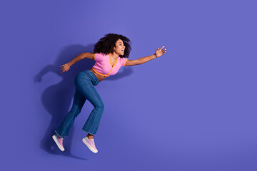 Young African-American Woman Running Forward Against Vibrant Purple Background Expressing Joy