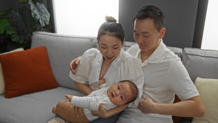 Fototapeta premium Mother, father, and baby boy in living room share a moment of love and joy as they sit together on a cozy sofa in their home.