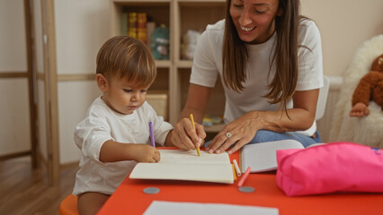 Woman and son engaged in a drawing activity at a colorful playroom, highlighting learning, creativity, and togetherness in a warm kindergarten setting.