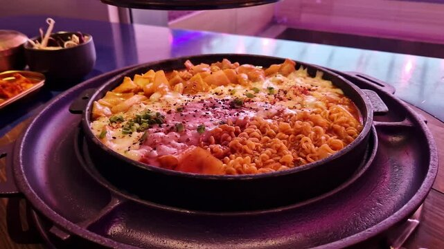 Takgalbi. Grilled patel with marinated chicken, tteokbokki, cabbage, noodles and mozzarella. Korean food. Delicious food in a restaurant. Hot food in a grilled patel