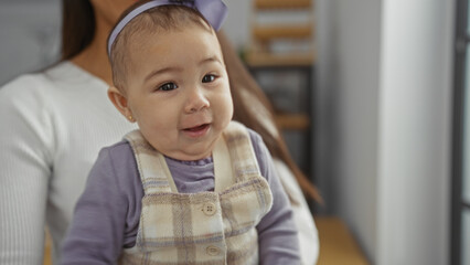 Baby girl in mother's arms indoors, showcasing family love in a home setting, surrounded by a warm and cozy interior, emphasizing maternal bonding.