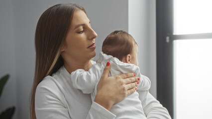 Woman holding baby in a bright indoor room, embodying a tender family love moment during the day.