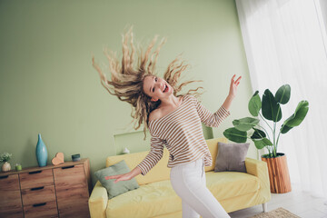 Joyful young woman with blond hair enjoying a relaxing weekend at home, dressed in striped pullover...