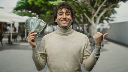 Hispanic man smiling with bangladesh taka standing outdoors on a city street near a coffee shop...