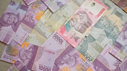 Indonesian rupiah banknotes scattered on a flat surface showcasing various denominations and colors