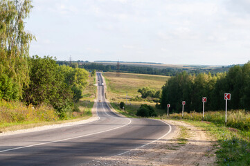 Beautiful view of asphalt road through fields and forests, sharp turn and steep descent