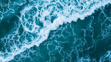 Fototapeta premium Aerial ocean waves crashing scene suitable for travel brochures, website banners, environmental conservation materials, and coastal tourism promotions.