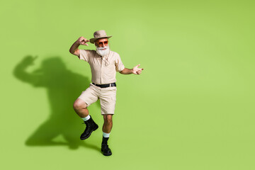 Elderly man in a safari outfit with a green background, portraying adventurous spirit and tourism