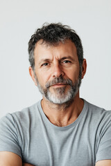 Fototapeta premium A close-up portrait photograph depicts a mature man with short, graying hair and a prominent graying beard. The image is sharply focused on his face, revealing detailed textural elements such as