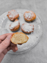 Hand holding fluffy donut, boortsog, boorsok half with icing sugar on glass plate in prague