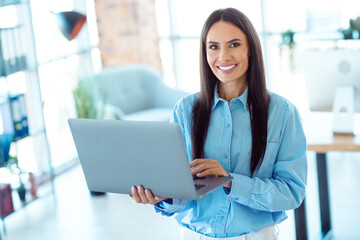 Fototapeta premium Professional businesswoman working on a laptop in a bright modern office setting, exuding confidence and professionalism