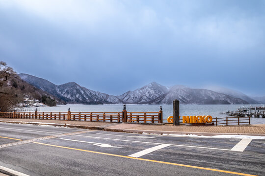 Lake Chuzenji, on the mountains in Nikko, Japan, during winter season with snow fall under cloudy sky and very cold weather. Japanese letters were name of public gate in Japanese faith.