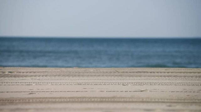 Tranquil beach with tire tracks and calm sea horizon