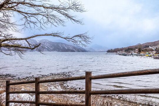 Lake Chuzenji, on the mountains in Nikko, Japan, during winter season with snow fall under cloudy sky and very cold weather. Japanese letters were name of public gate in Japanese faith.