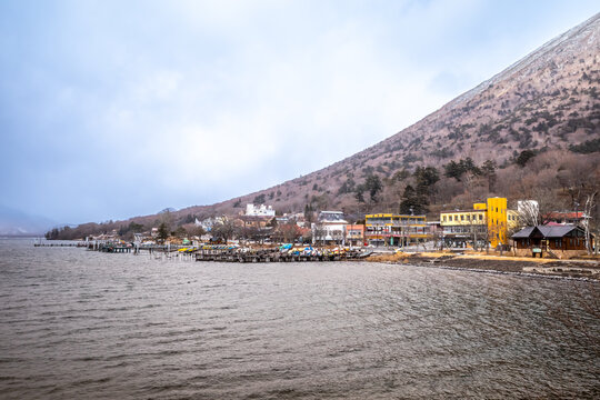Lake Chuzenji, on the mountains in Nikko, Japan, during winter season with snow fall under cloudy sky and very cold weather. Japanese letters were name of public gate in Japanese faith.