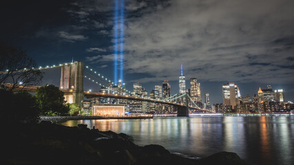 Fototapeta premium Night view during 9 11 of lower Manhattan and the Brooklyn Bridge with the Tribute in Light in the background