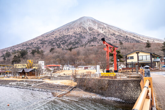 Lake Chuzenji, on the mountains in Nikko, Japan, during winter season with snow fall under cloudy sky and very cold weather. Japanese letters were name of public gate in Japanese faith.