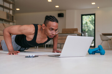 Training At Home. Sporty african american man doing the training while watching an online tutorial...