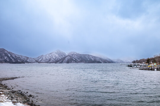 Lake Chuzenji, on the mountains in Nikko, Japan, during winter season with snow fall under cloudy sky and very cold weather. Japanese letters were name of public gate in Japanese faith.