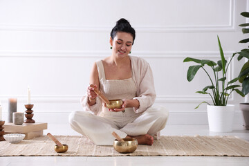 Woman with singing bowls on floor indoors