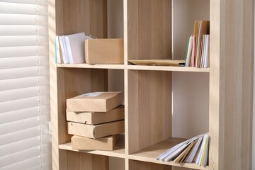 Different paper envelopes and parcels on wooden shelves in post office