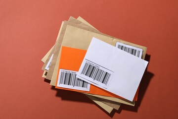 Different paper envelopes on red-brown background, top view. Post office