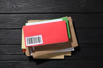 Different paper envelopes on black wooden table, top view. Post office