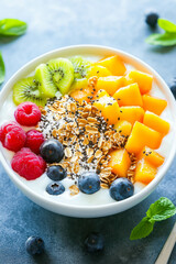 Vibrant yogurt bowl with fresh fruit and granola on blue background