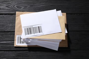 Different paper envelopes on black wooden table, top view. Post office