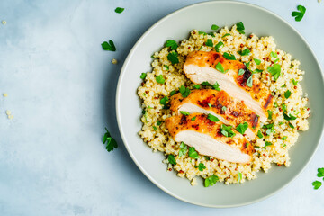 Grilled chicken breast on quinoa with fresh herbs garnished on a plate