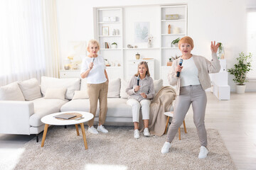 Obraz premium Senior woman singing karaoke with friends at home