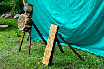 A close up on two archery targets made out of boards, planks, and logs utilized by archers to improve their bow and crossbow skills seen with numerous holes and an arrow catcher made out of cloth