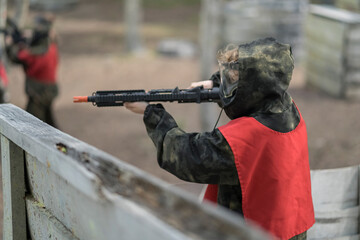 Kids playing airsoft. Team gun play on an outdoor sports field