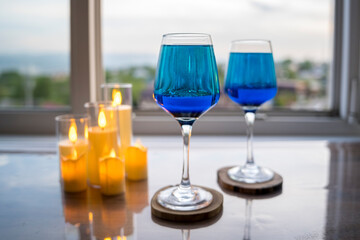 Glasses with a beautiful blue liquid in the background of the window