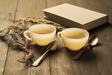 Warm Herbal Tea Served in Elegant Cups Alongside a Restful Book and Nature Elements