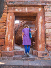 Woman exploring ancient temple site at Badami. Tourist walking among ruins stone walls gateways in Karnataka, India
