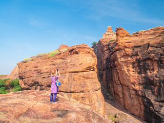 Woman exploring ancient temple site at Badami. Tourist walking among ruins stone walls gateways in Karnataka, India