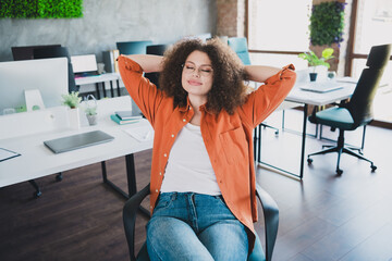 Young Businesswoman Relaxing in a Modern Office Workspace, Sitting Comfortably While Taking a Break...