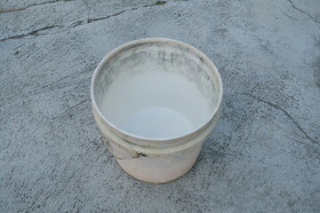 White liquid in a plastic bucket on concrete